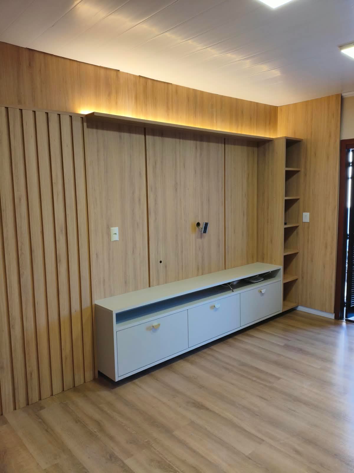 Home com painel amadeirado do piso ao teto — projeto executado pela Akai Móveis em Sapucaia do Sul