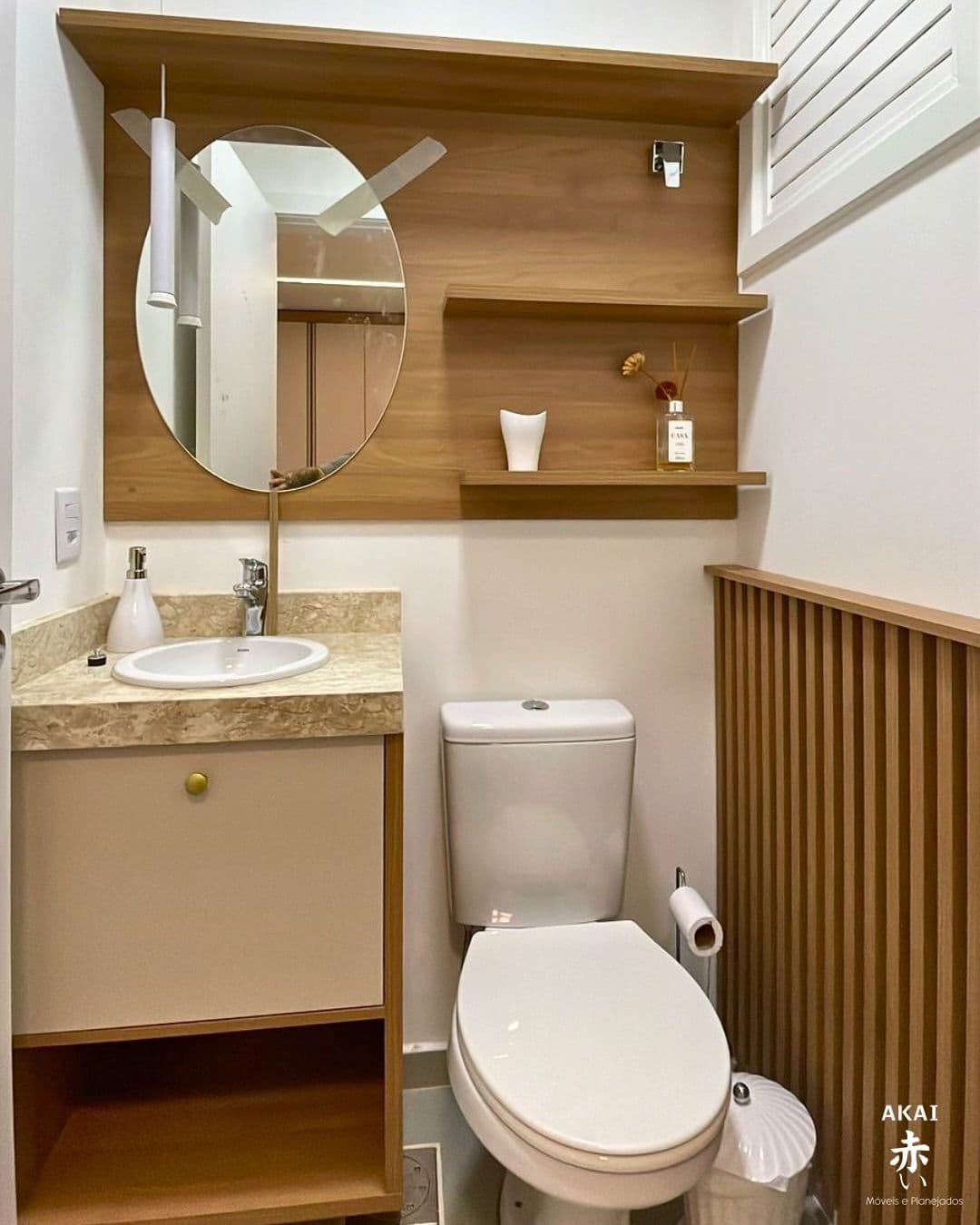 Lavabo com painel amadeirado e espelho oval — projeto executado pela Akai Móveis